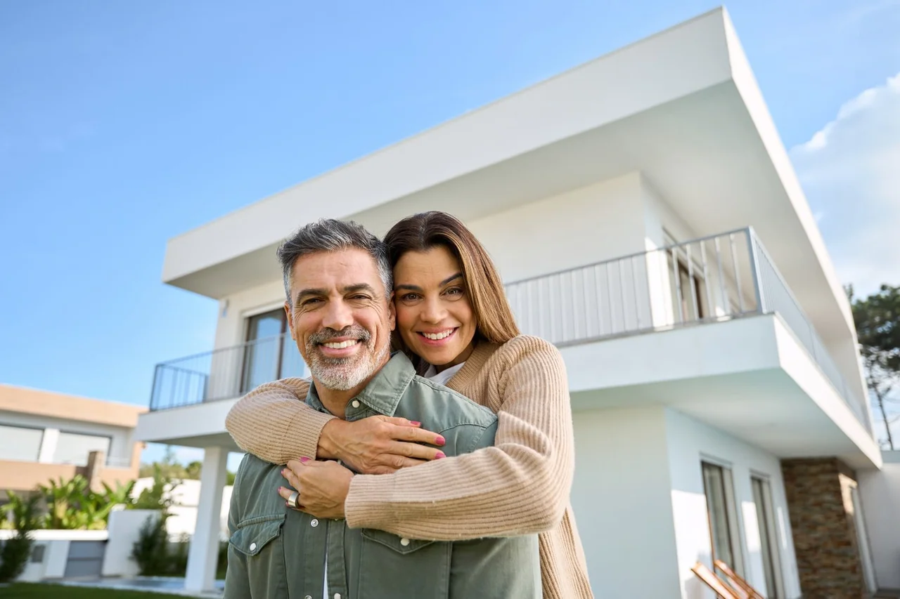 Happy homeowners standing outside their house